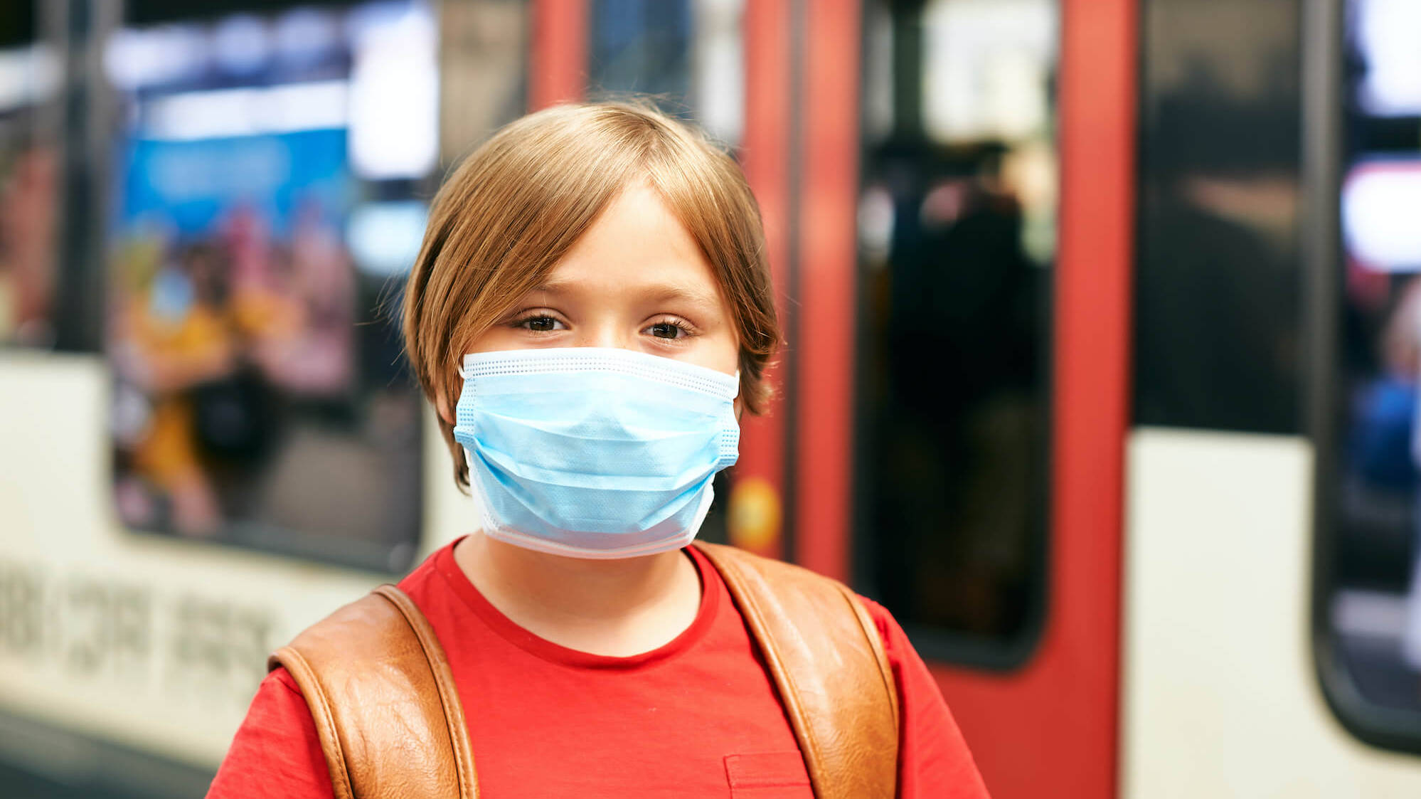 Schüler trägtr Maske und steht vor Straßenbahn